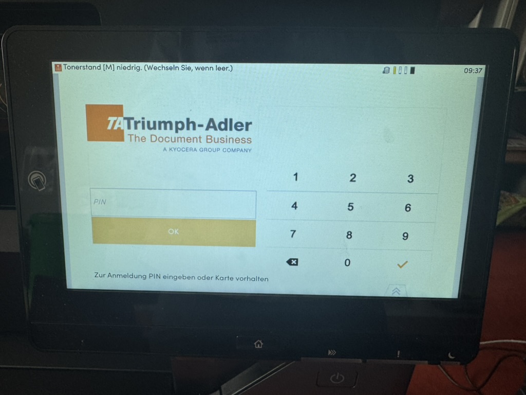 Anmeldebildschirm des Geräts, oben im Display die Meldung „Tonerstand [M] niedrig. (Wechseln Sie, wenn leer.)“