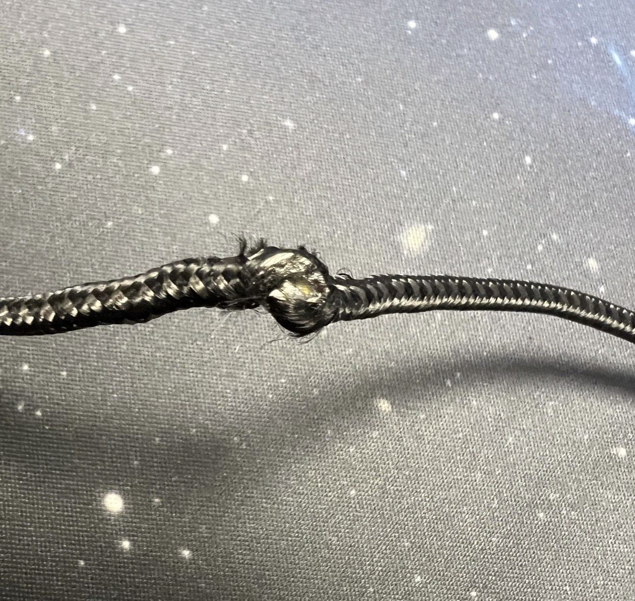 Geknicktes Ladekabel mit beschädigtem Geflecht in der Mitte des Kabels